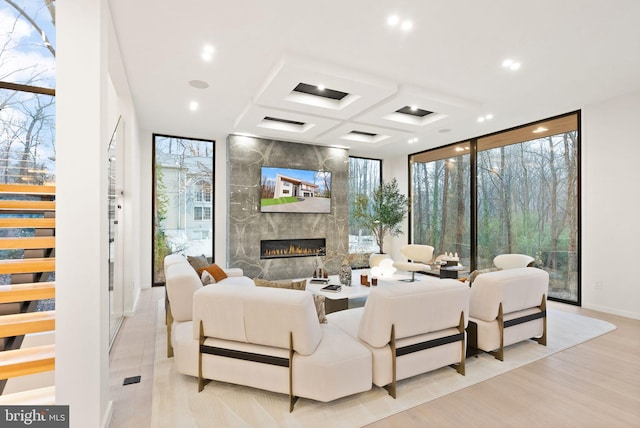 living room featuring coffered ceiling, a premium fireplace, wood finished floors, expansive windows, and recessed lighting