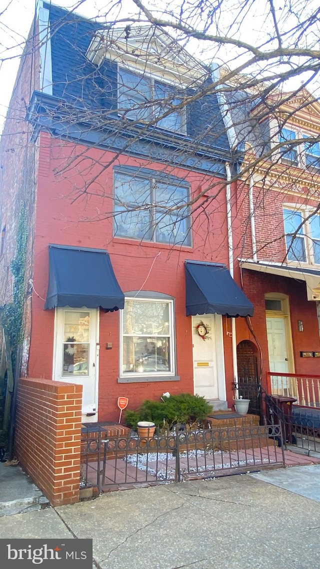 view of front facade with a fenced front yard, a gate, and brick siding