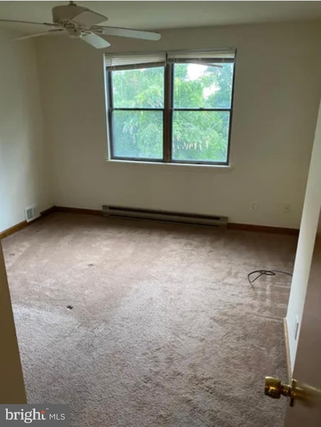 carpeted spare room featuring a baseboard heating unit, a wealth of natural light, visible vents, and baseboards