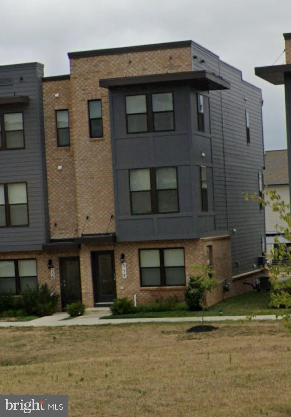 view of front facade featuring brick siding, cooling unit, and a front yard