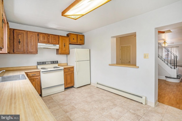 kitchen featuring white appliances, a sink, light countertops, under cabinet range hood, and baseboard heating