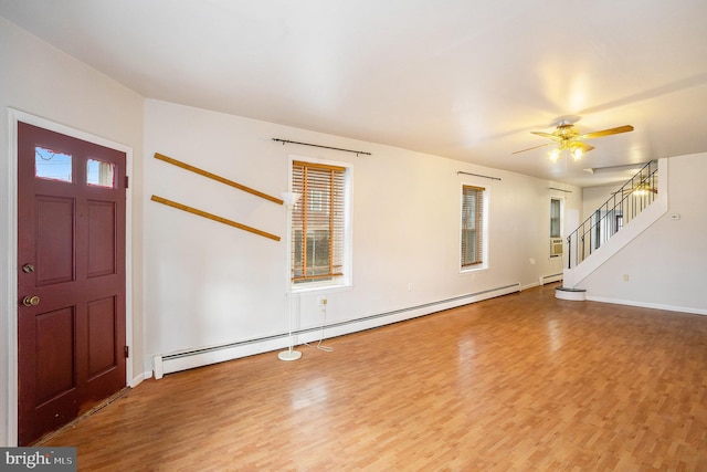 foyer with a baseboard radiator, wood finished floors, and stairs