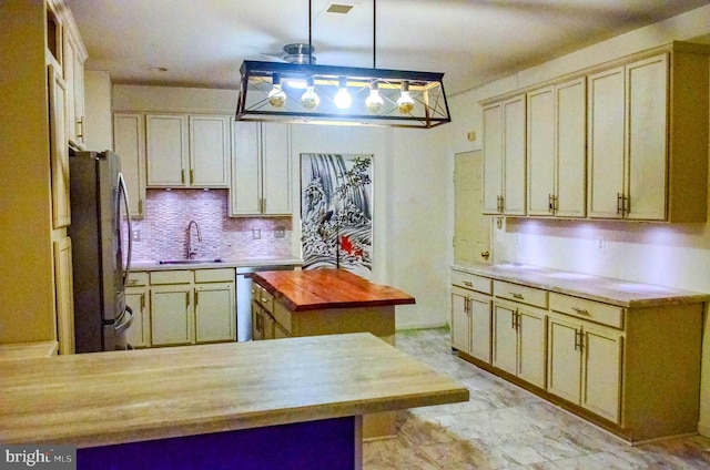 kitchen with hanging light fixtures, backsplash, freestanding refrigerator, a sink, and dishwasher