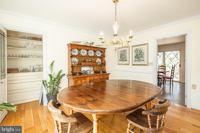 dining area featuring a notable chandelier, light wood-style floors, and ornamental molding