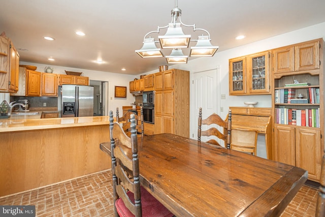 kitchen with a peninsula, brick floor, recessed lighting, and stainless steel refrigerator with ice dispenser