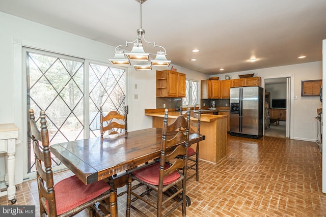 dining room featuring a notable chandelier, recessed lighting, baseboards, and brick floor