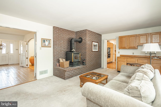 living room with visible vents, light carpet, and a wood stove