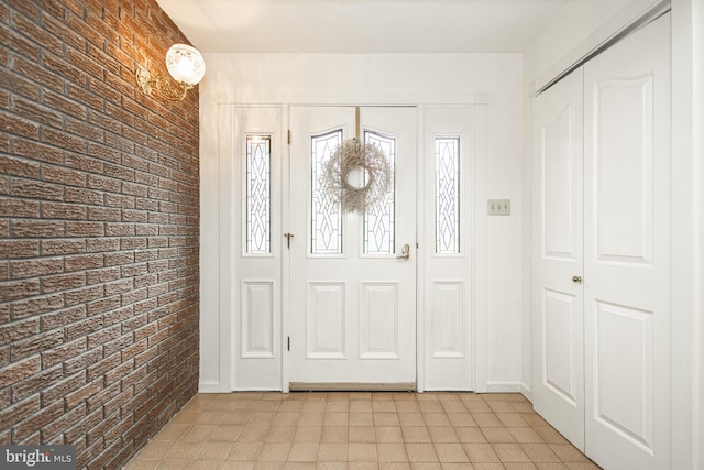 foyer with light floors and brick wall