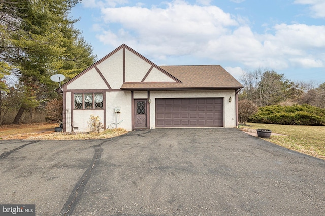 view of front of home featuring stucco siding, a garage, a shingled roof, and aphalt driveway