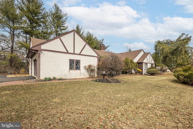 view of home's exterior with a lawn, a chimney, and stucco siding