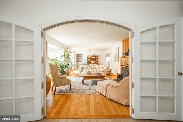 living area featuring built in features, arched walkways, a glass covered fireplace, and hardwood / wood-style floors