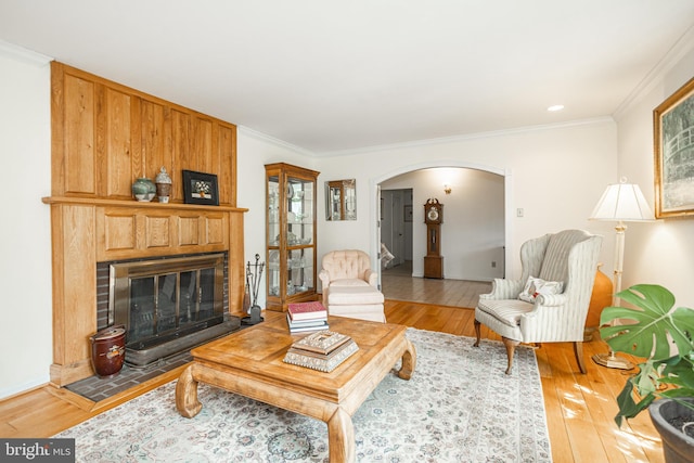 living room with crown molding, arched walkways, and light wood finished floors