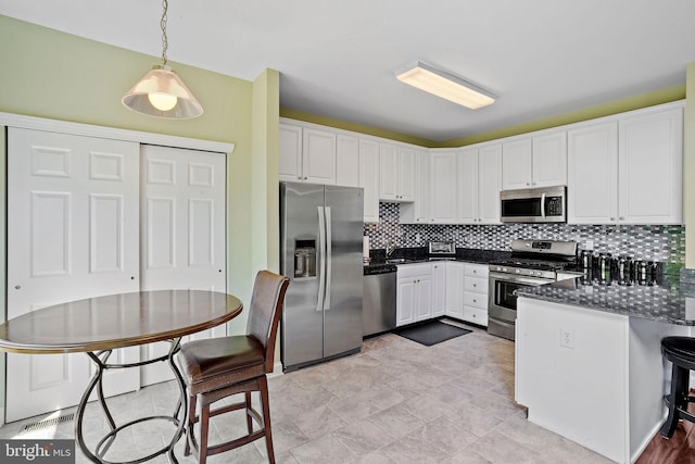 kitchen featuring stainless steel appliances, white cabinetry, a peninsula, and tasteful backsplash