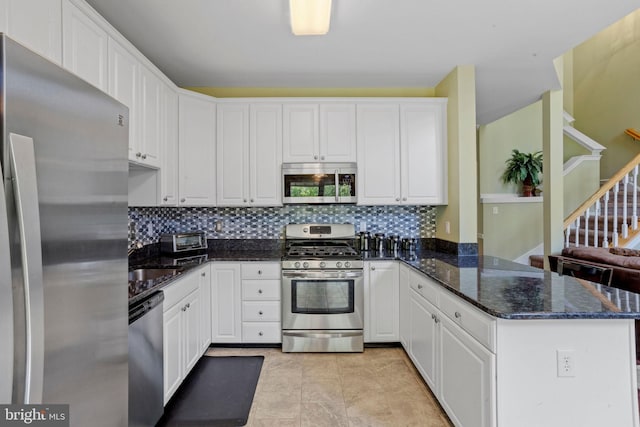 kitchen featuring a peninsula, white cabinets, stainless steel appliances, and backsplash