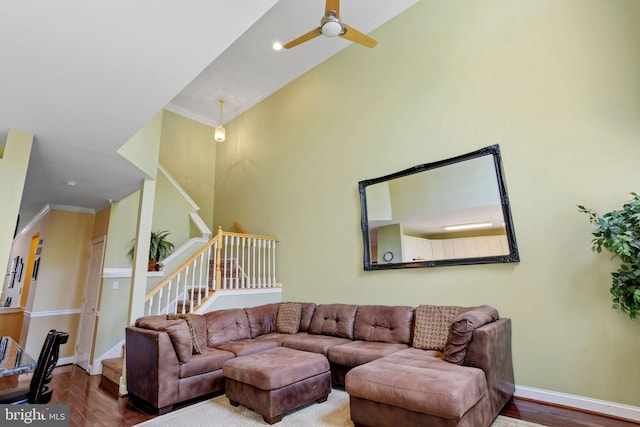 living room featuring stairs, baseboards, wood finished floors, and crown molding