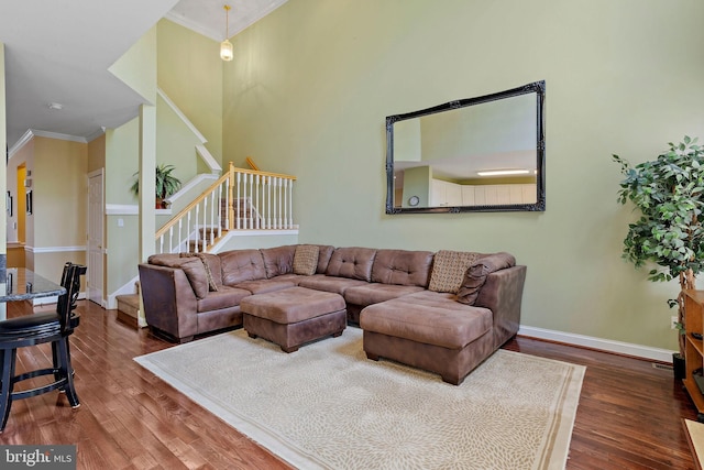 living area featuring stairs, baseboards, wood finished floors, and crown molding