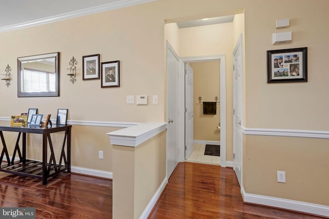 corridor featuring baseboards, wood finished floors, an upstairs landing, and crown molding