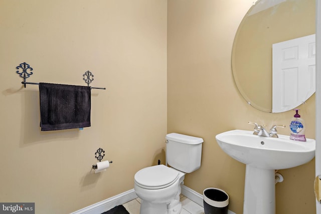 bathroom with toilet, tile patterned flooring, baseboards, and a sink