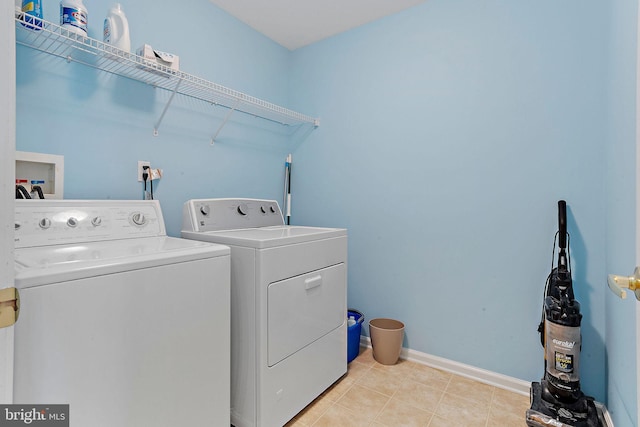 washroom with laundry area, washing machine and dryer, light tile patterned floors, and baseboards