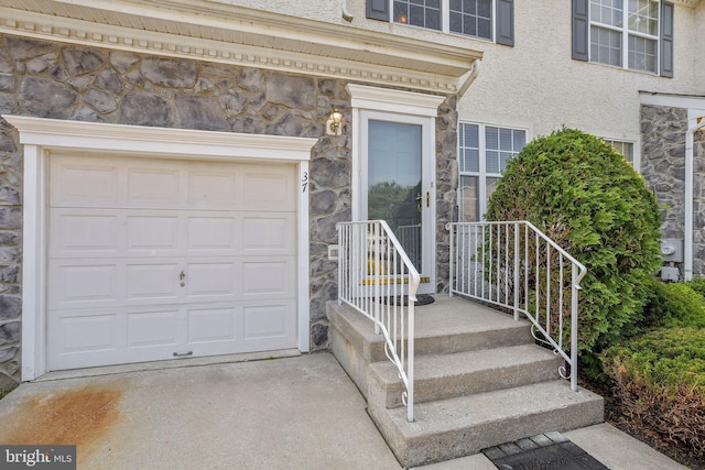 view of exterior entry with stone siding, concrete driveway, and stucco siding