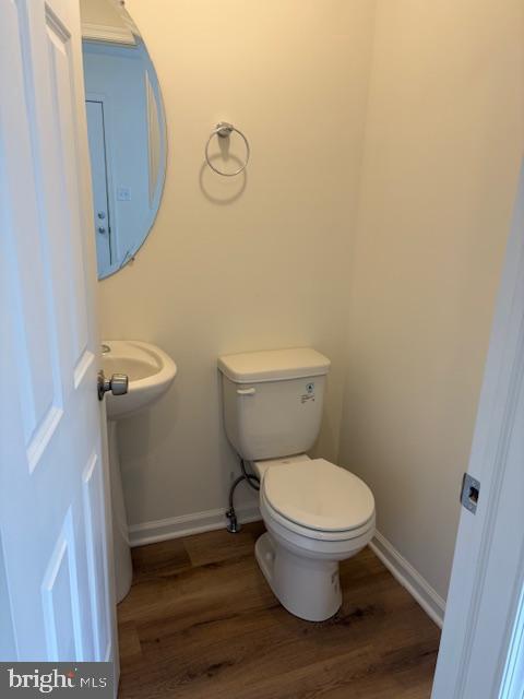 bathroom featuring toilet, baseboards, and wood finished floors