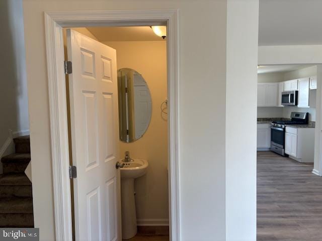 corridor featuring stairs, baseboards, and wood finished floors