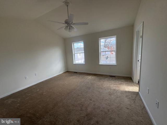 carpeted spare room featuring ceiling fan, lofted ceiling, and baseboards