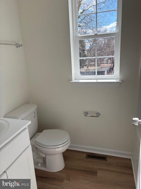 bathroom with vanity, wood finished floors, baseboards, visible vents, and toilet