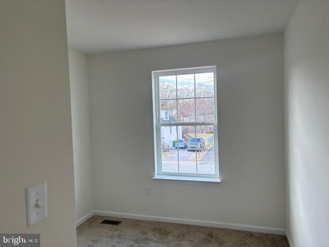 empty room with carpet flooring, visible vents, and baseboards