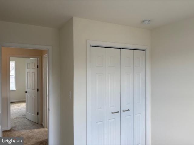 unfurnished bedroom featuring baseboards, a closet, and light carpet