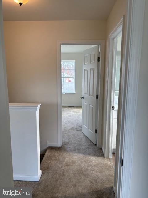 hall featuring carpet flooring and baseboards