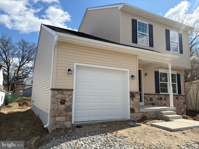 view of front of home featuring stone siding, driveway, and a garage