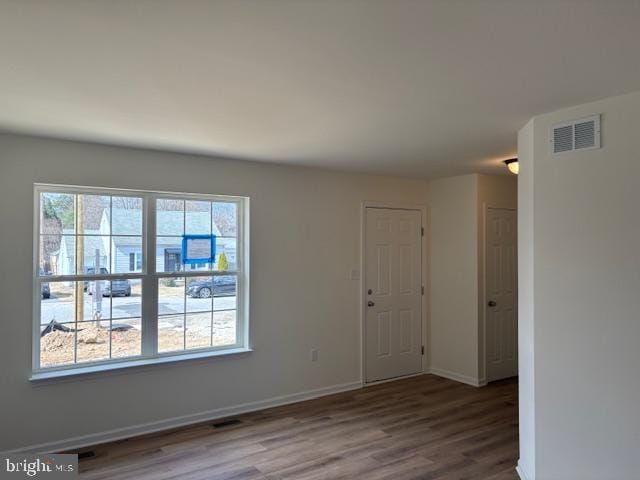 empty room featuring visible vents, baseboards, and wood finished floors