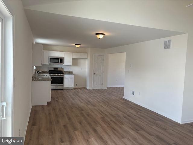 kitchen with visible vents, wood finished floors, stainless steel appliances, white cabinets, and baseboards