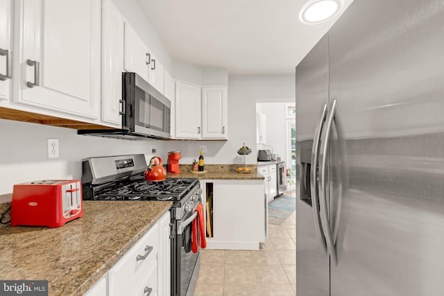 kitchen featuring stainless steel appliances, light tile patterned flooring, light stone countertops, and white cabinets