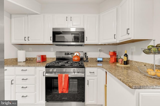 kitchen with stainless steel appliances, light stone countertops, and white cabinets