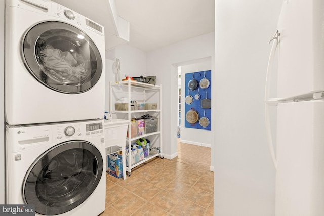 washroom with light tile patterned floors, laundry area, stacked washer and clothes dryer, and baseboards