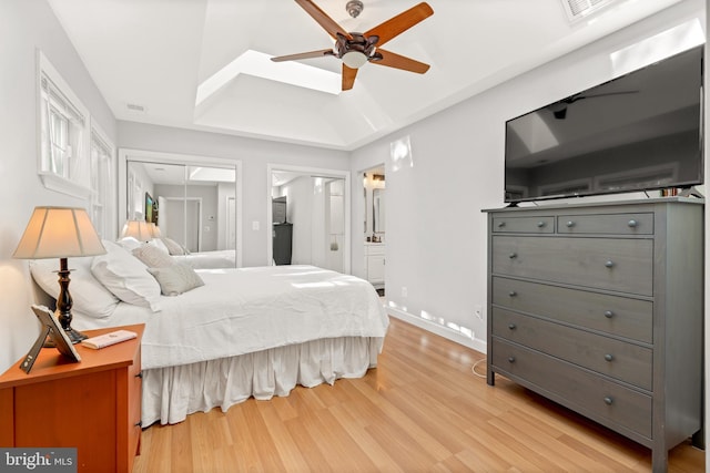 bedroom with ensuite bath, light wood-style flooring, visible vents, and attic access