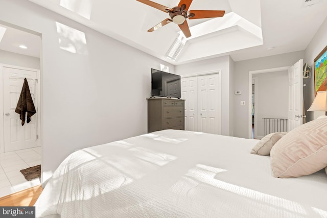 tiled bedroom with ceiling fan, a raised ceiling, a closet, and recessed lighting