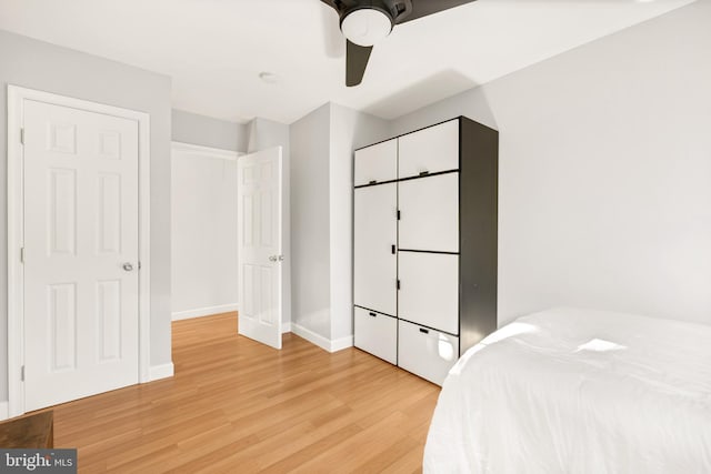 bedroom featuring a ceiling fan, baseboards, and light wood finished floors