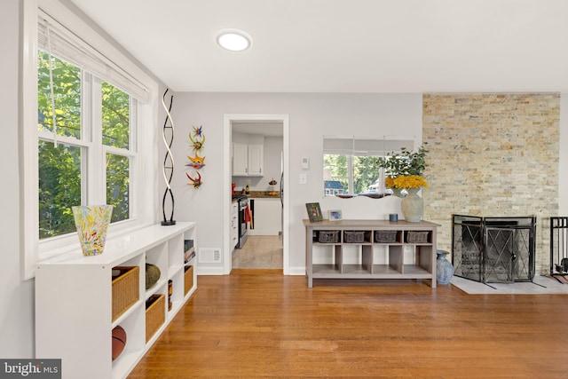 living area with plenty of natural light, a fireplace, visible vents, and wood finished floors