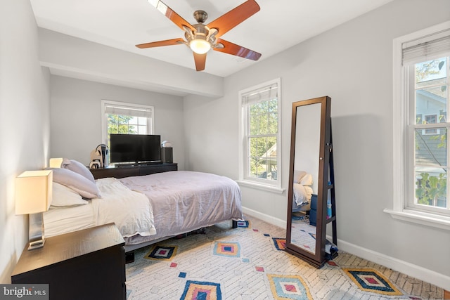 bedroom featuring multiple windows, a ceiling fan, and baseboards