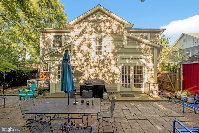 back of property with a patio, french doors, outdoor dining space, and fence