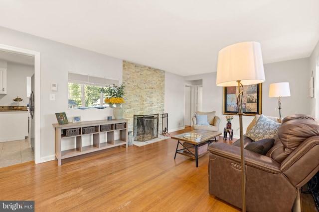 living room with light wood finished floors, a fireplace, and baseboards