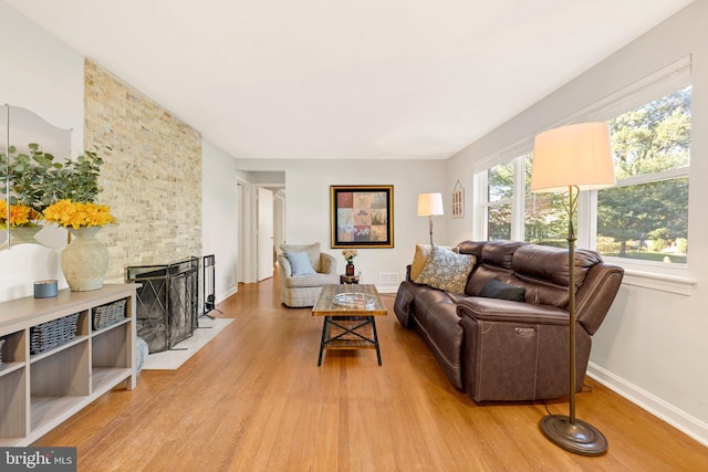 living room featuring light wood finished floors, baseboards, a fireplace, and visible vents