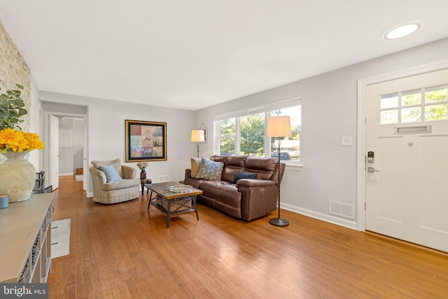 living area with baseboards, visible vents, and light wood finished floors