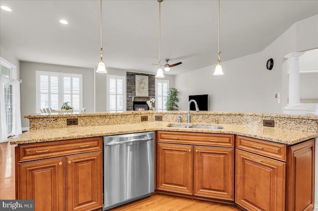 kitchen featuring a fireplace, a sink, stainless steel dishwasher, light stone countertops, and ornate columns