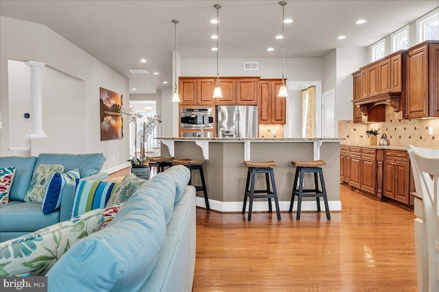 living room with light wood-type flooring, visible vents, ornate columns, and recessed lighting