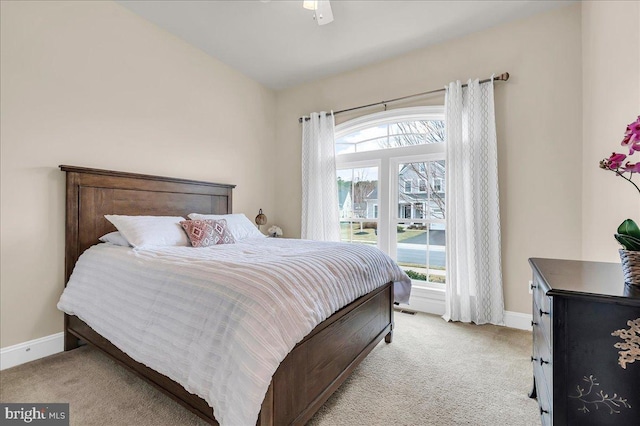 bedroom featuring light carpet, a ceiling fan, and baseboards