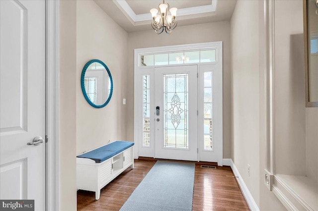 entrance foyer featuring a chandelier, a raised ceiling, wood finished floors, and baseboards